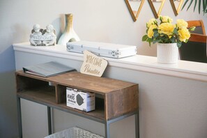 A reception desk with a welcome sign, a white vase with yellow flowers, a white suitcase, and a 3D mask box. - Private Pool, Spa & Game Room 4BR La Quinta (La Quinta)