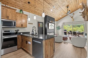 A modern kitchen with wooden cabinets, stainless steel appliances, and a central island. - Bungalow Bliss | NEW | Swim Spa 💦 Private Fire Pit 🔥 (Hollister)