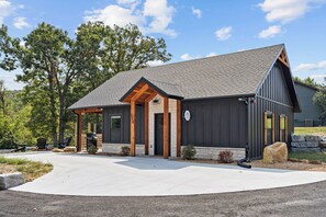 A modern building with a stone foundation, a sloped roof, and a covered porch area. - Bungalow Bliss | NEW | Swim Spa 💦 Private Fire Pit 🔥 (Hollister)