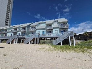 A beachfront hotel with multiple balconies, a sandy beach in front, and a clear blue sky. - Ocean Reef 901 Family Friendly 3-bedroom Townhome (Gulf Shores)