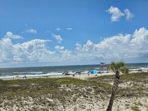 A beach with a clear sky, waves, and a palm tree. - Ocean Reef 901 Family Friendly 3-bedroom Townhome (Gulf Shores)