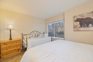 Ein Schlafzimmer mit zwei Betten, einem Holzschrank, einer Lampe und einem Fenster mit Blick.