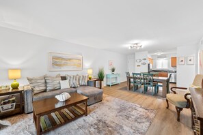 Ein modernes Wohnzimmer mit einer Couch, einem Couchtisch und einem Essbereich mit Stühlen.