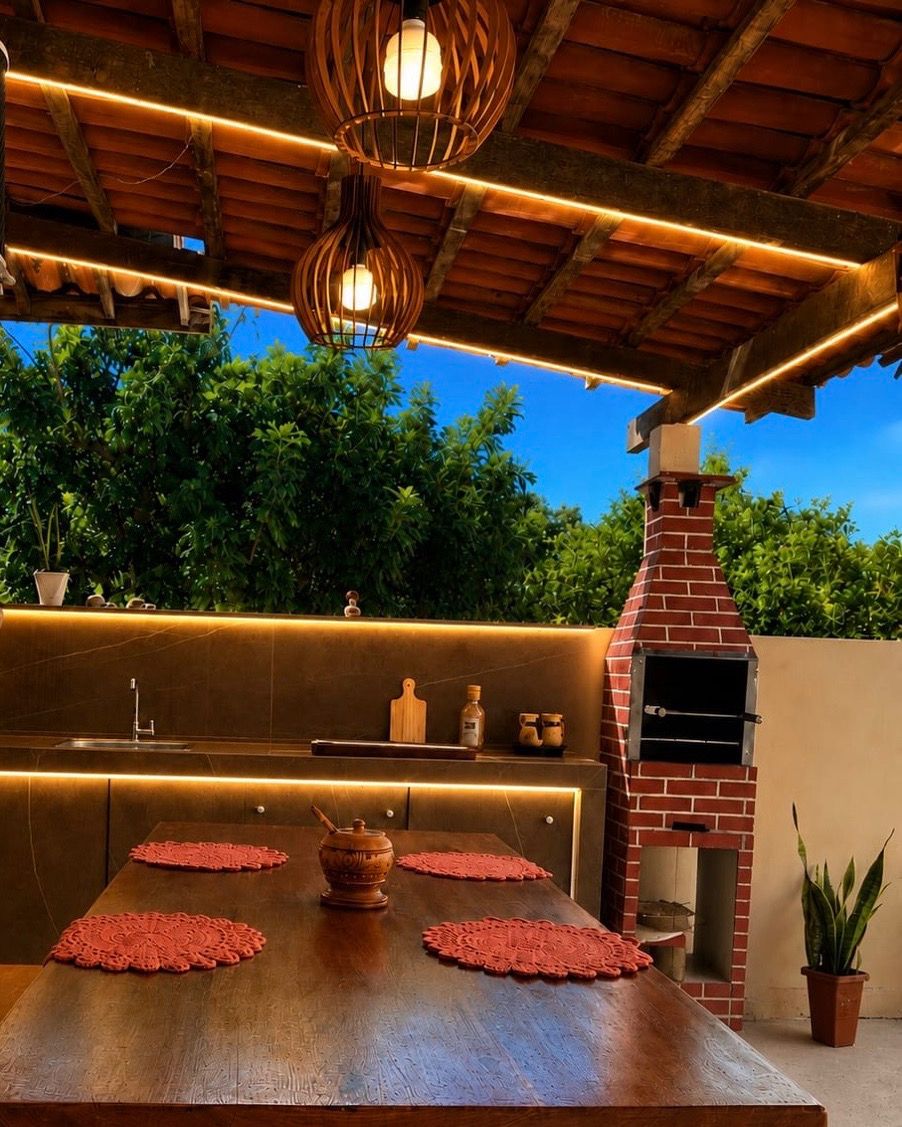 An outdoor dining area with a brick oven, wooden table, and red placemats.