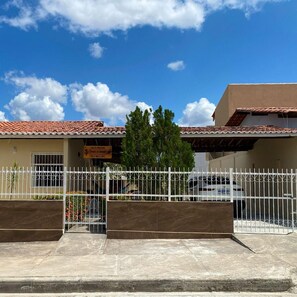A building with a tiled roof, a gated entrance, and a sign indicating a business. - Holiday home with capacity for up to 10 people, 30m from the shopping center. (Piranhas)