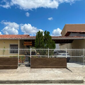 A building with a tiled roof, a gated entrance, and a signboard. - Holiday home with capacity for up to 10 people, 30m from the shopping center. (Piranhas)