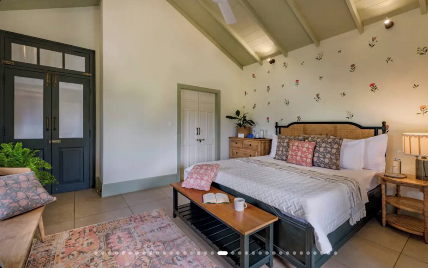 Een slaapkamer met een bed, nachtkastje, lamp en een deur.