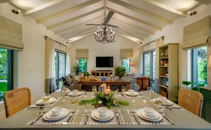 A dining area with a high ceiling, chandelier, and a television.