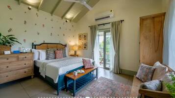 Een slaapkamer met een bed, nachtkastje, lamp en uitzicht op het groen.