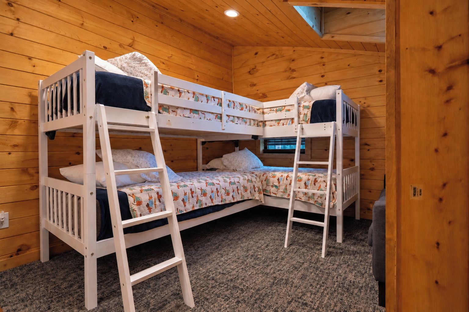 A bunk bed room with wooden walls and carpet flooring.
