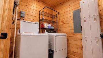 A compact laundry room with a washing machine, dryer, and a metal shelf with detergent bottles.