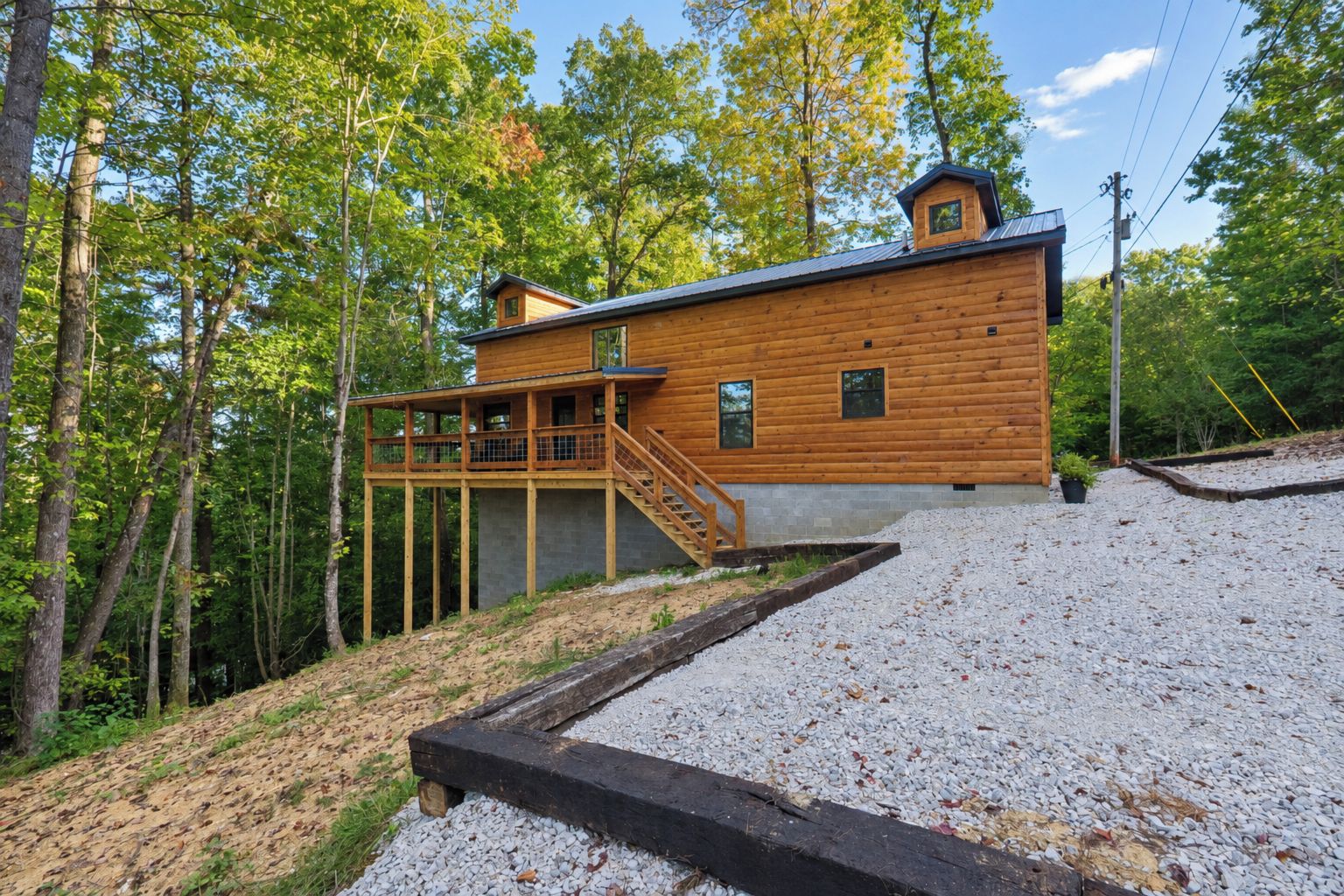 A wooden cabin with a deck and stairs, surrounded by trees.