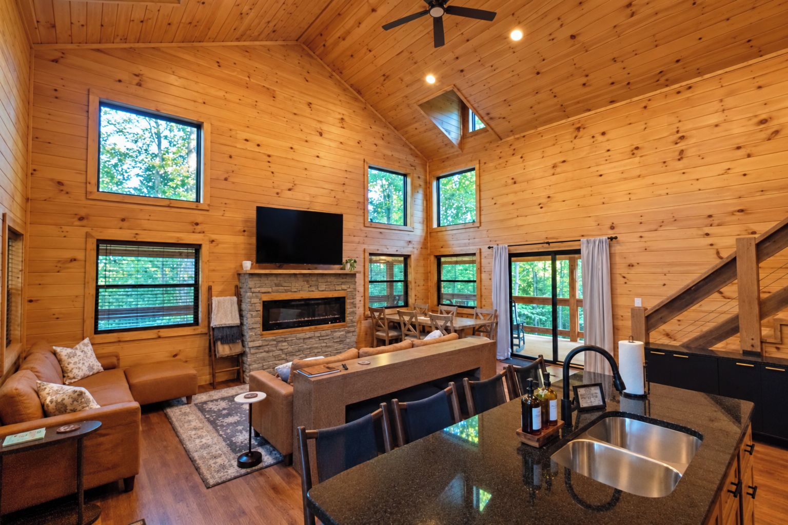 L’intérieur d’une cabane en rondins comprend une cheminée, un téléviseur, un coin repas et une cuisine équipée d’un évier.