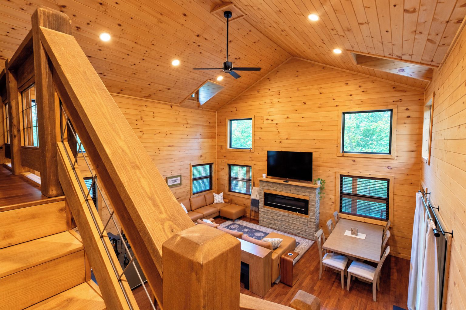 A wooden cabin interior with a fireplace, a TV, and a dining area.