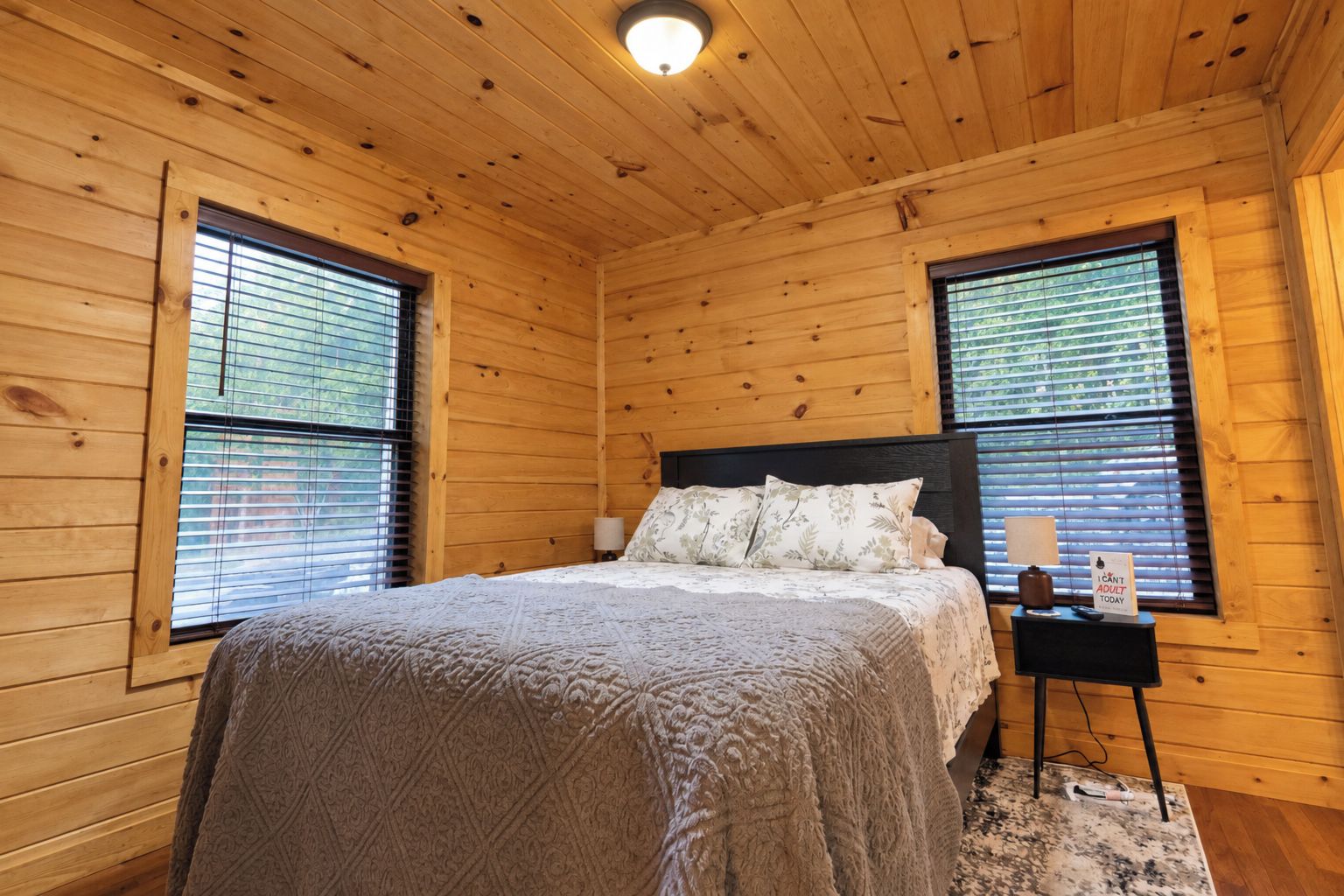 A wooden-paneled bedroom with a bed, two bedside tables, and a nightstand.