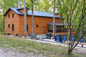 A log cabin with a deck, outdoor seating, and a grill.