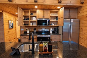 A compact kitchen with wooden cabinets, a stainless steel refrigerator, a microwave, and a coffee maker. - Gorge Haven | Hot Tub • Near Muir Valley (Rogers)