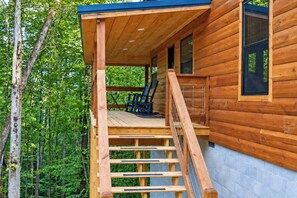 Une cabane en bois avec une véranda couverte, un escalier et une fenêtre.