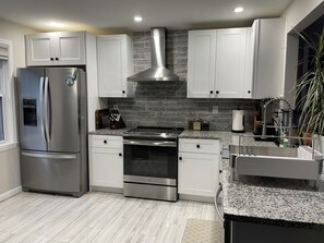 A modern kitchen with stainless steel appliances, white cabinetry, and a granite countertop. - Peaceful Homestead: 2BR/2BA + Office & Garden (Decatur)
