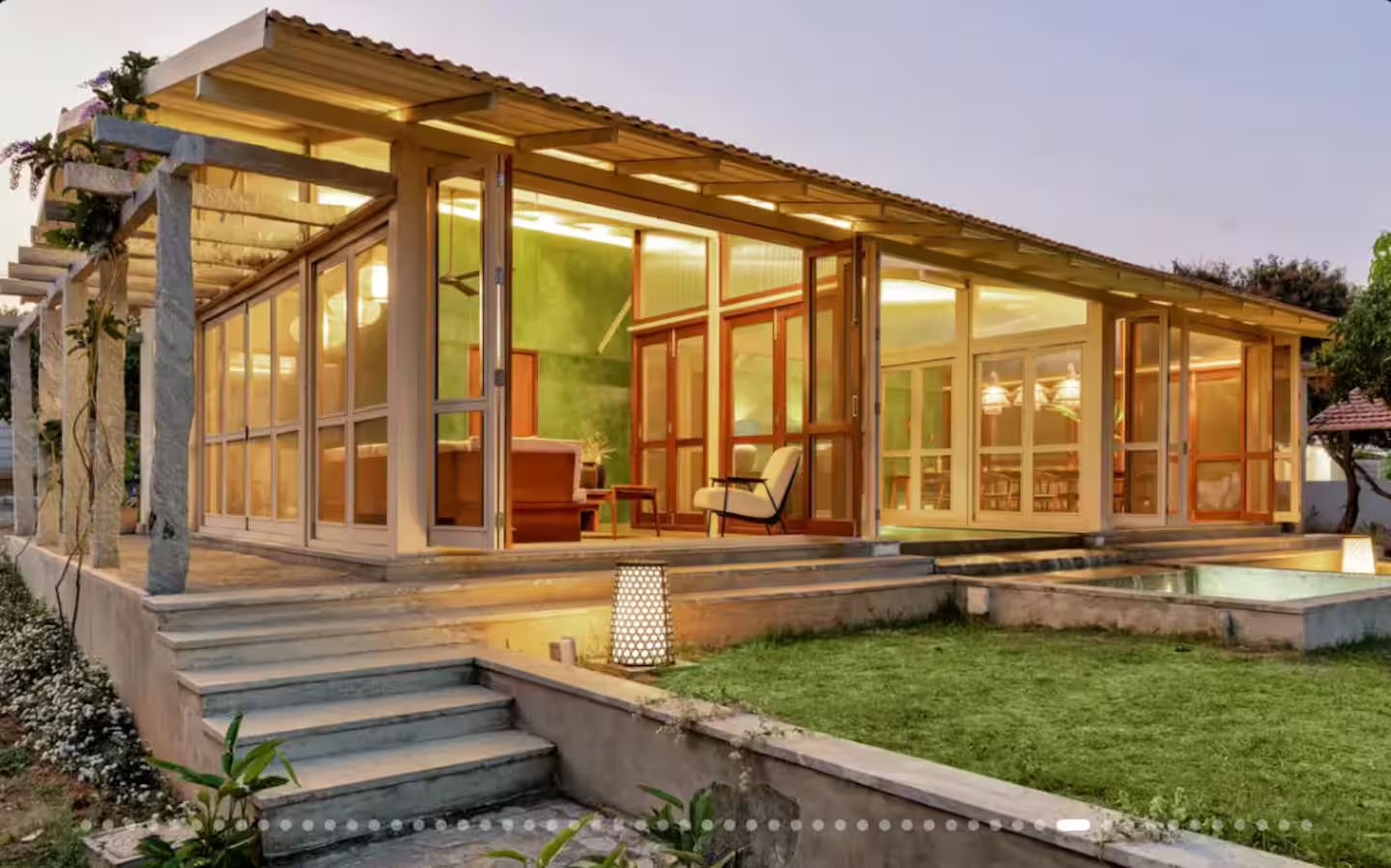 Ein modernes Haus mit überdachter Terrasse, Swimmingpool und gepflegtem Rasen.