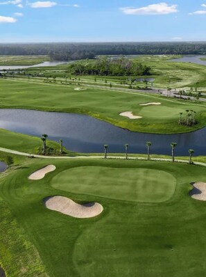 A golf course with sand bunkers, water hazards, and a clear sky. - Calusa Country Club | Golf Included | 2BR Condo (Bradenton)
