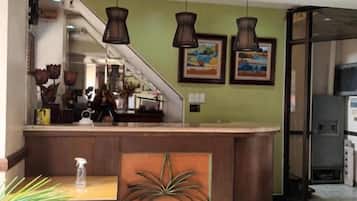 A reception desk with a sign for 'Mactan Pension House,' a staircase, and a view of the interior.