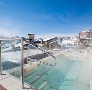 A hot spring pool with a glass barrier, surrounded by buildings with snow-covered roofs. - Ski-in/Ski-Out Sheraton Steamboat Villas - 1 Bedroom Premium Mountainview (Steamboat Springs)