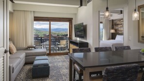 Quarto de hotel moderno com varanda, área de refeições e quarto com uma cama grande.
