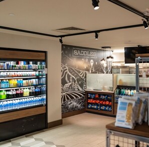 A beverage kiosk with a variety of drinks and a wall mural advertising 'SADDLES LOUNGE + MARKET'. - Ski-in/Ski-Out Sheraton Steamboat Villas - 1 Bedroom Premium Mountainview (Steamboat Springs)