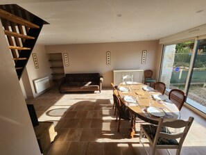Ein Essbereich mit einem Tisch für vier Personen, einer Couch und einer Treppe, die in eine obere Ebene führt.