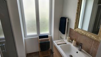 Une salle de bain avec une baignoire, un lavabo, un miroir et une fenêtre.