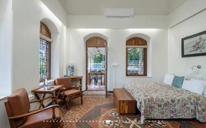 A room with a bed, a desk, chairs, and a window. - Vintage Heritage Villa with Lawns & Garden Retreat (Lonavala)