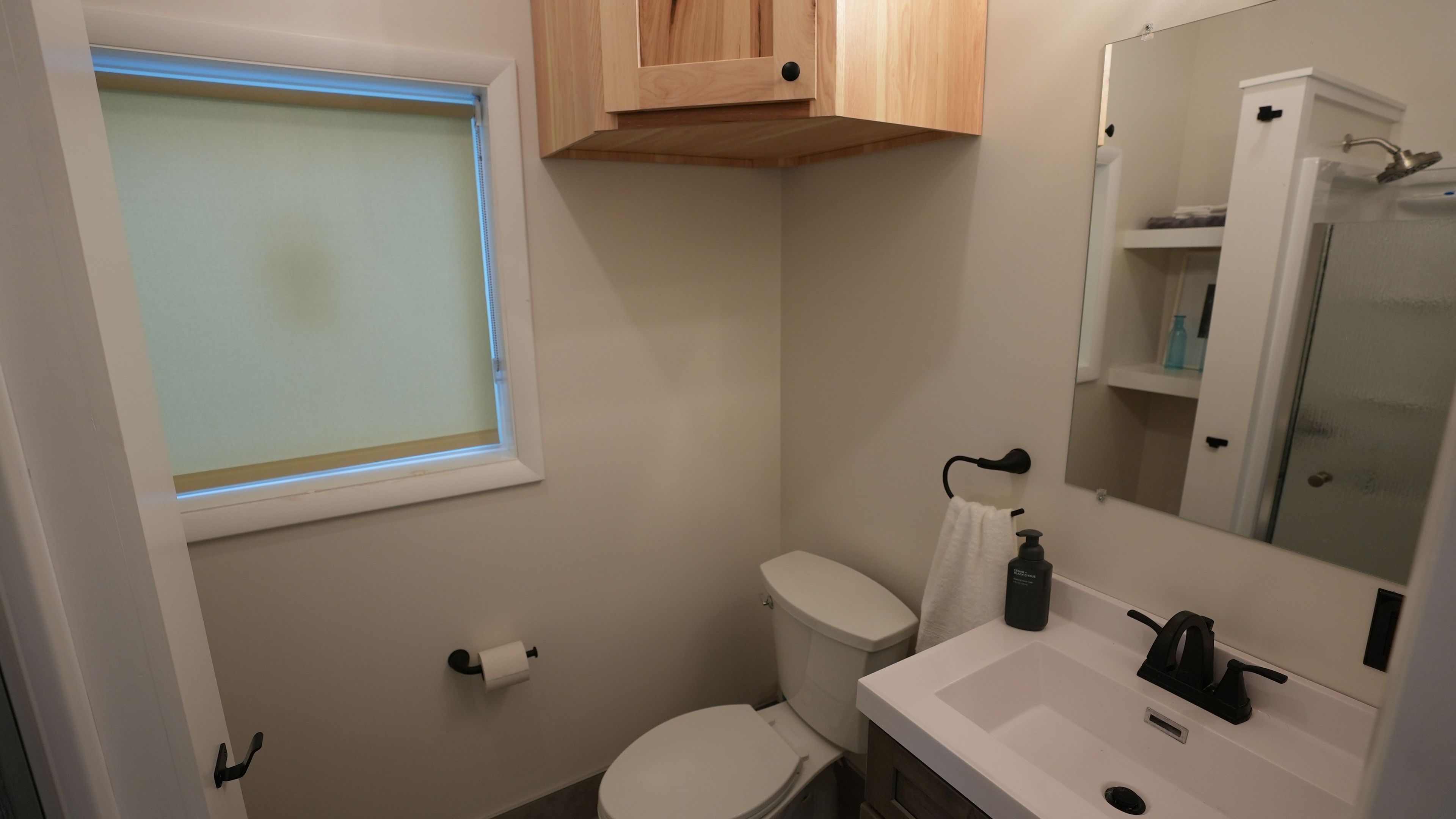 Un baño con inodoro, lavamanos, espejo y ventana.