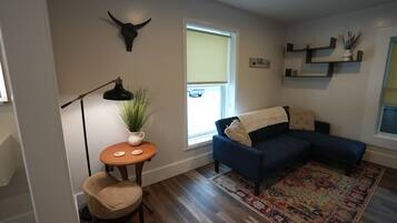 A living room with a blue sofa, a round table with a plant, a lamp, and a bull skull decoration.