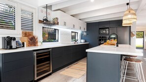 Cozinha moderna com adega embutida, máquina de café e uma ilha grande com banquetas.