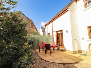A patio area with outdoor furniture, a wooden fence, and a building with a white exterior. - Derwent Cottage (Cockermouth)