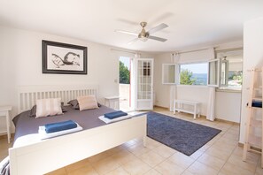 A bedroom with a bed, a ceiling fan, a window with a view, and a door leading outside. - Spacious Villa Colombes with Panoramic Views, Air Conditioning, and Infinity Pool (Draguignan)