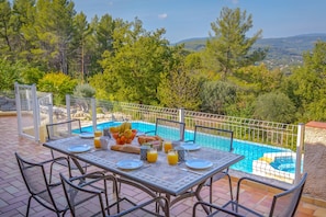 An outdoor dining area with a table set for breakfast, overlooking a swimming pool and a scenic landscape. - Spacious Villa Colombes with Panoramic Views, Air Conditioning, and Infinity Pool (Draguignan)
