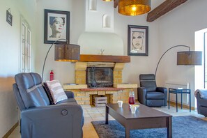 A living room with a fireplace, leather sofas, a coffee table, and artwork on the walls. - Spacious Villa Colombes with Panoramic Views, Air Conditioning, and Infinity Pool (Draguignan)