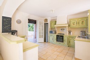 A kitchen with green cabinets, a microwave, and a coffee machine. - Spacious Villa Colombes with Panoramic Views, Air Conditioning, and Infinity Pool (Draguignan)