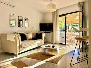 Ein modernes Wohnzimmer mit einer Couch, einem Flachbildfernseher und einem Essbereich mit Tisch und Stühlen.