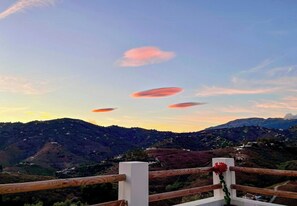Vista panorámica de un paisaje montañoso con una cerca de madera y una planta en maceta.
