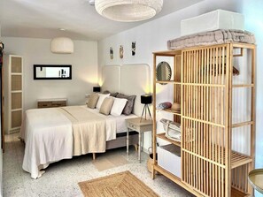 Un dormitorio con cama, mesita de noche, lámpara y una estantería de madera.