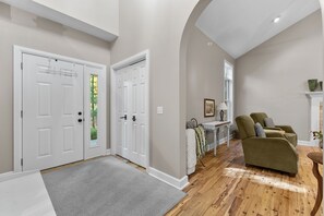 A spacious living room with a wooden floor, a green sofa, and a fireplace. - Woodhaven - Deer Park 39 (Glen Arbor)