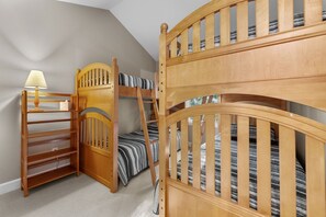 Ein Zimmer mit Etagenbetten, einer Holzleiter, einem Schreibtisch und einer Lampe.