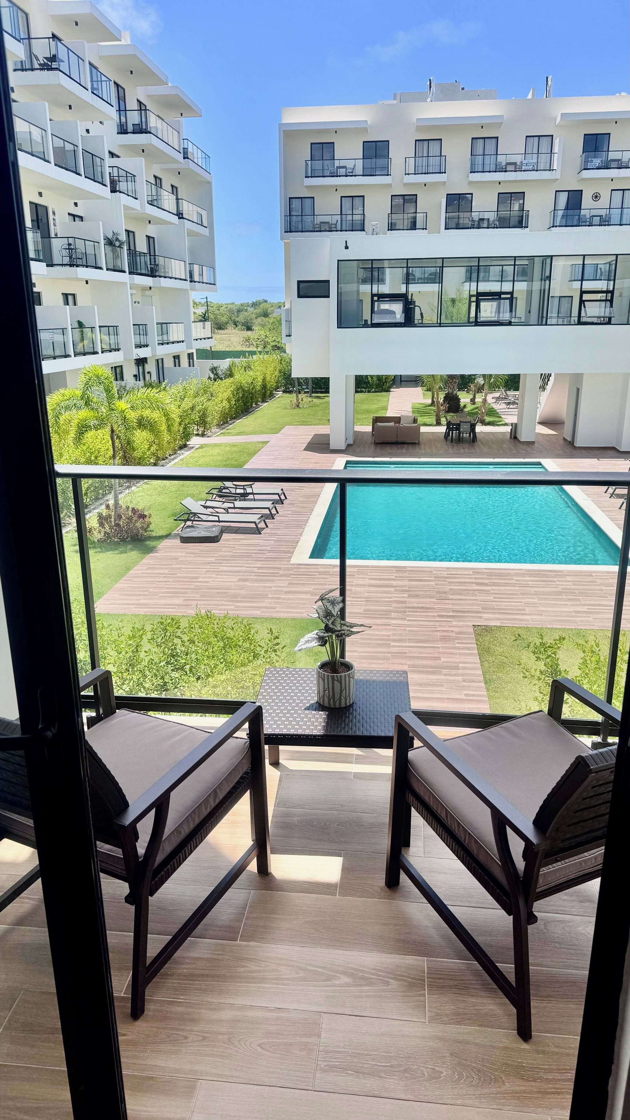 A balcony with a view of a swimming pool and a modern building in the background.