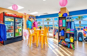 Ein strandthematisches Restaurant mit einem Coca-Cola-Kühlschrank, bunten Stühlen und Blick auf den Ozean.