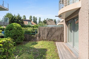 A residential property with a fenced backyard, a wooden deck, and a modern building with large windows. - Delvaux B 001 met garage (NIEUWPOORT)