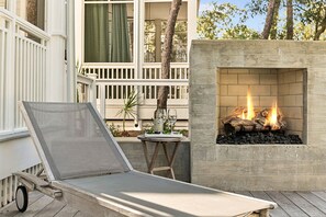 A lounge chair, a small table with a bottle and glass, and a fireplace with logs. - Lakefront | Private Pool | LSV (Santa Rosa Beach)