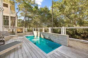 Una piscina amb terrassa de fusta, gandules i una zona amb foc.
